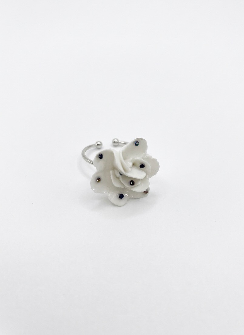 A white rose shaped ceramic ring on a plain white background
