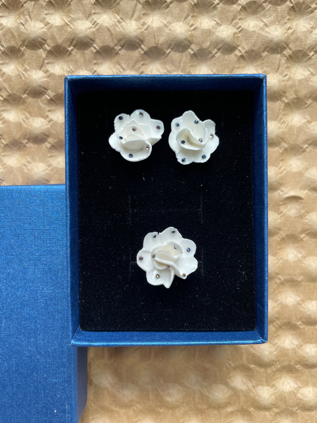 Three white ceramic flower shapes in a blue velvet box