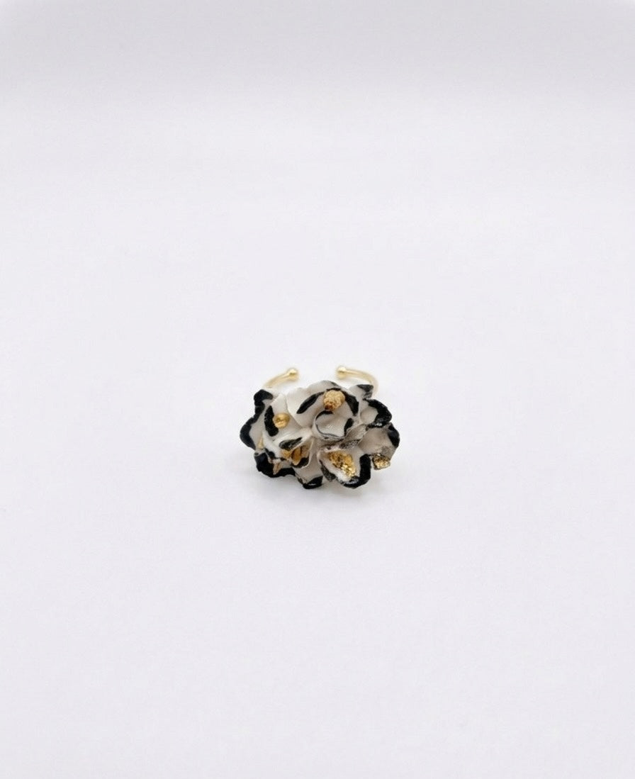 A white and black floral ring with gold details on a white background