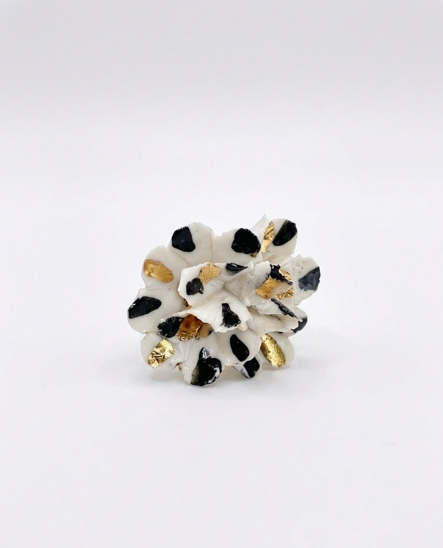 White ceramic flower sculpture with black spots and gold leaf accents